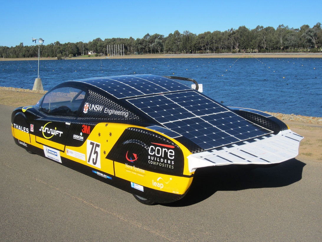 Ein aerodynamischer Solar-Rennwagen, Symbol für Materialinnovationen und Forschungsprojekte im Automobilsektor, geparkt an einem Gewässer.